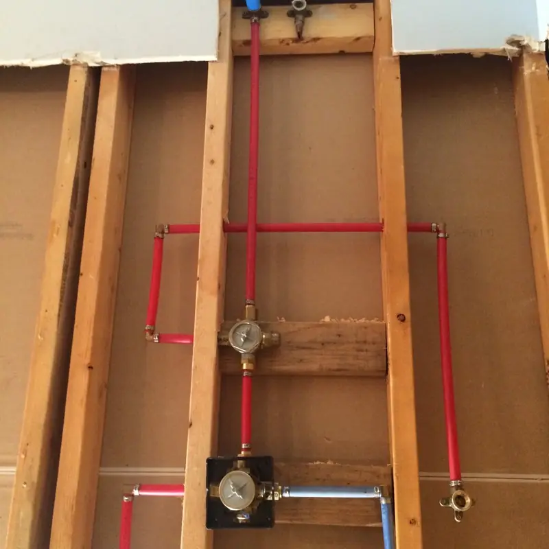 A new shower valve roughed in with red and blue supply lines between the wall studs