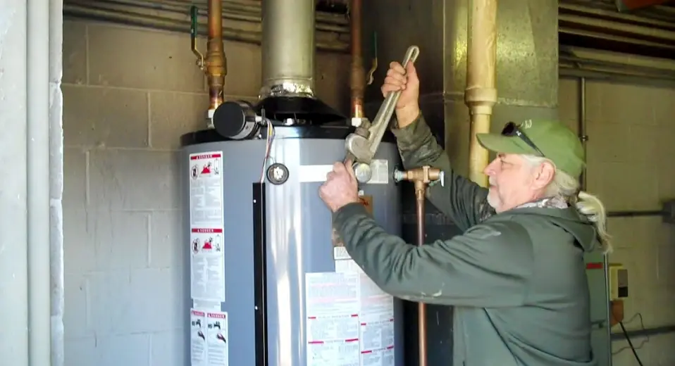 A Hansen plumber tightening a fitting on a newly installed gas water heater